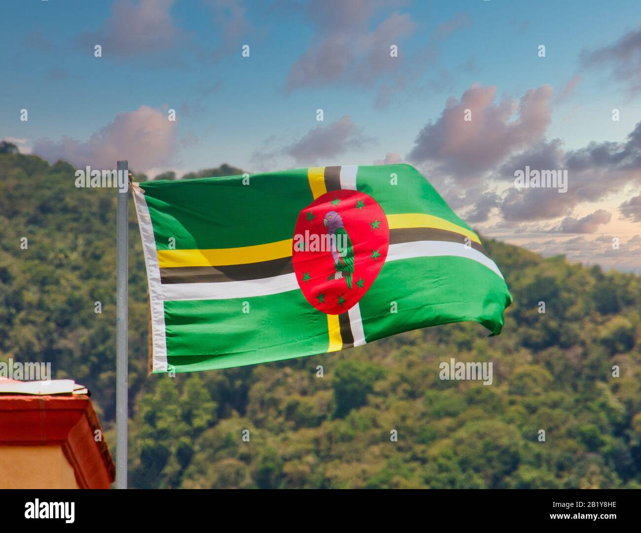 Flagge von Dominica, die gegen tropische Hügel bei Dsuk fliegt Stockfoto