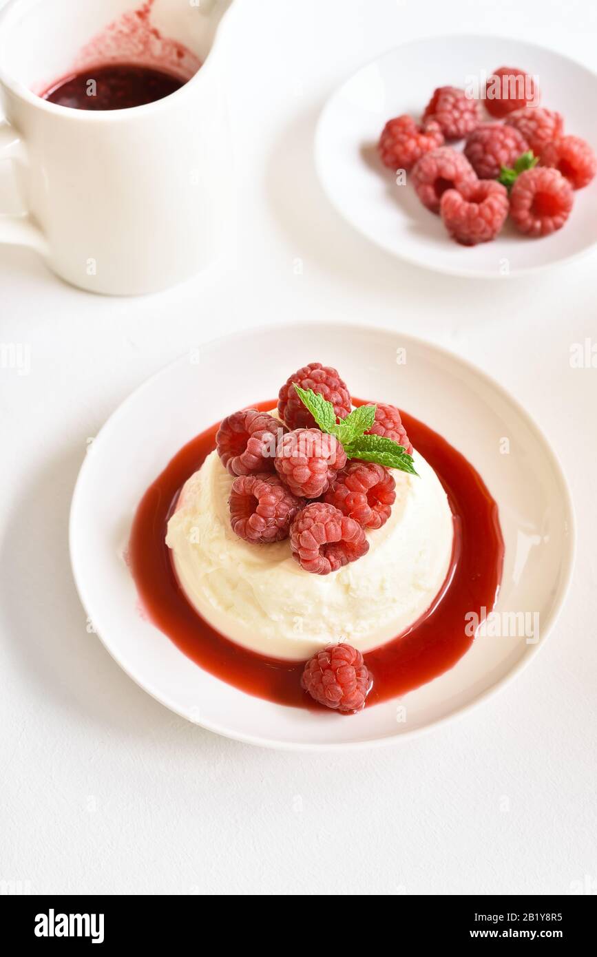 Panna Cotta mit frischen Himbeeren in Schüssel auf Steingrund. Köstliches Dessert. Nahansicht Stockfoto