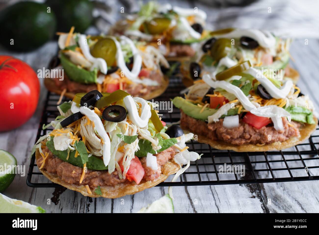 Hausgemachte Hühnerstadas mit gebratenen Pinto Bohnen, frischem Cilantro, geschredderten Cheddar-Käse, Avocados, schwarzen Oliven, saurer Sahne, Salat, Jalapenos, l. Stockfoto