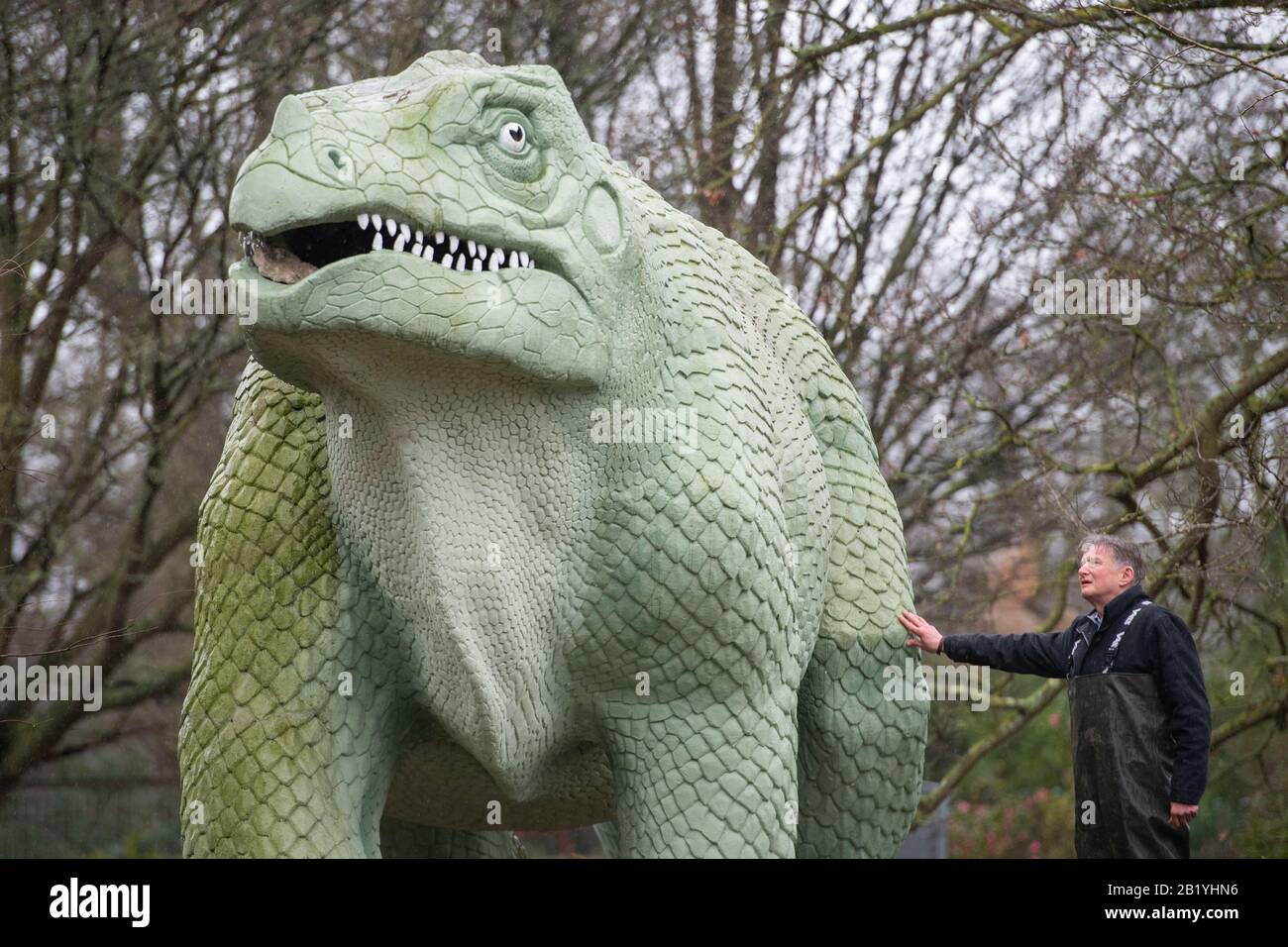 Simon Buteux aus Dem Historischen England mit einer Iguanadon-Skulptur, Teil der Crystal Palace Dinosuars, im Crystal Palace Park, London. Die in den 1850er Jahren errichteten 30 Grade-I-Statuen wurden in das "Heritage at Risk Register" Des Historischen Englands aufgenommen, nachdem Experten große Risse an den Körpern und Gliedmaßen und Gefahr des Verlustes von Zehen, Zähnen und Schwänzen gefunden hatten. Stockfoto