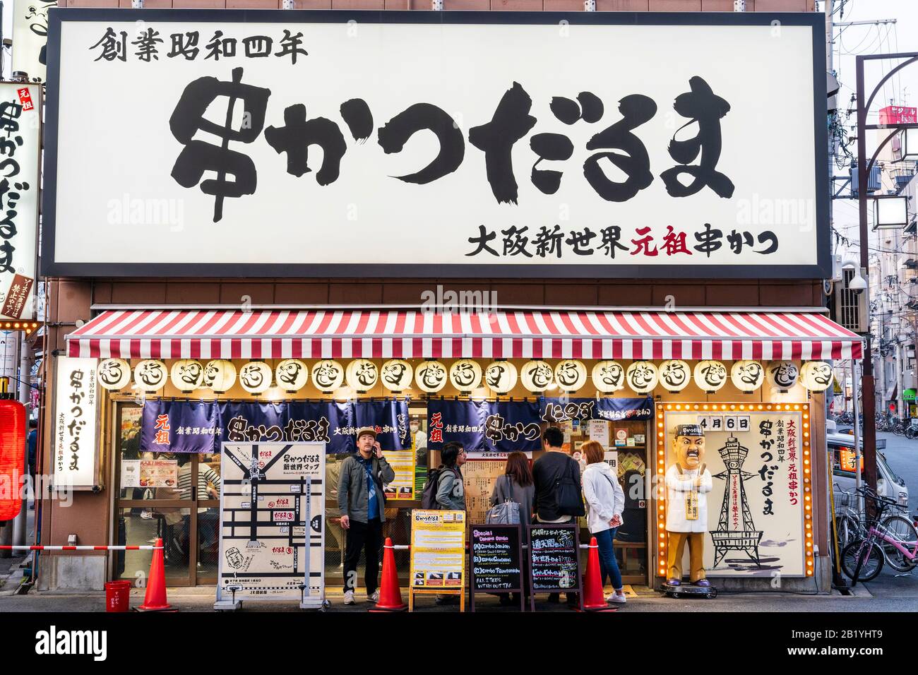 Das ursprüngliche Restaurant Kushikatsu aus dem Jahr 1929, Ganso Kushikatsu Daruma in Shinsekai, Osaka. Verärgerter Koch, Diner-Logo, Statue draußen auf dem Straßenbelag. Stockfoto