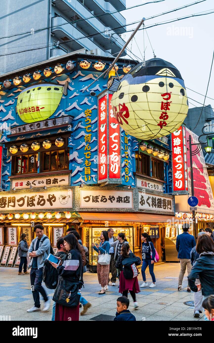 Shinsekai, Osaka, das Restaurant Zuboraya mit seinem beleuchteten Puffer-Fischschild, das während der blauen Abendstunde über der Fußgängerzone hängt. Stockfoto