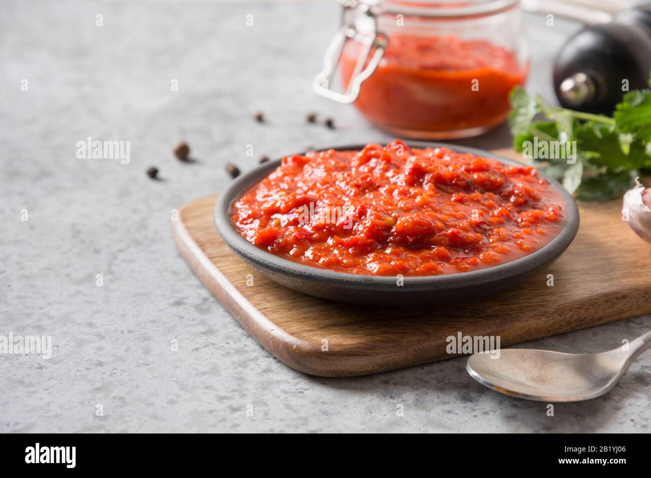 Lecker ajvar. Gemüsesauce oder Kaviar gebackener roter Paprika auf Grau. Balkanküche. Horizontale Ausrichtung. Leerzeichen für Text.Nahaufnahme. Stockfoto