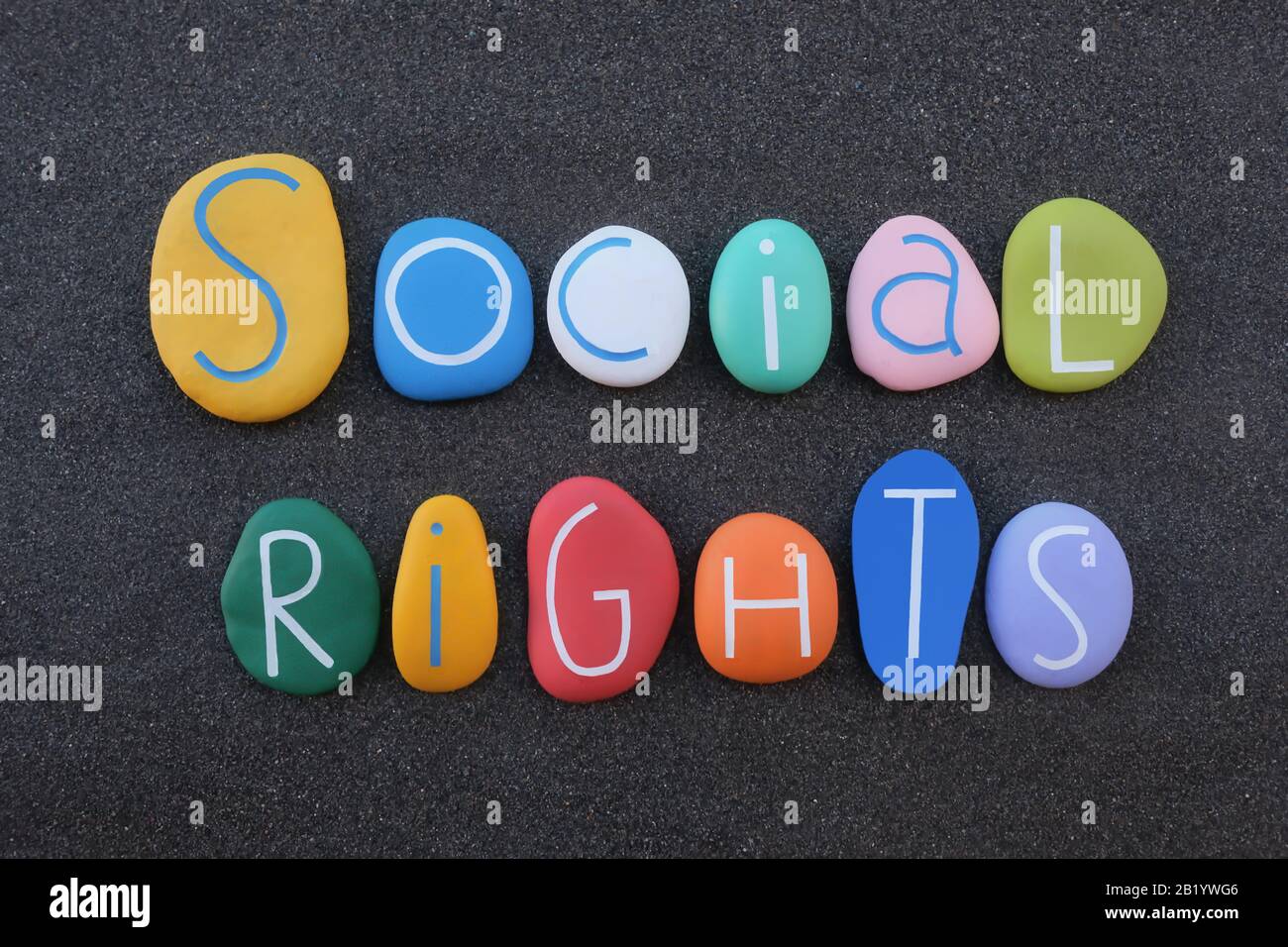 Soziale Rechte, Sozialvertragslehre, Text mit mehrfarbigen Steinbuchstaben über schwarzem Vulkansand Stockfoto