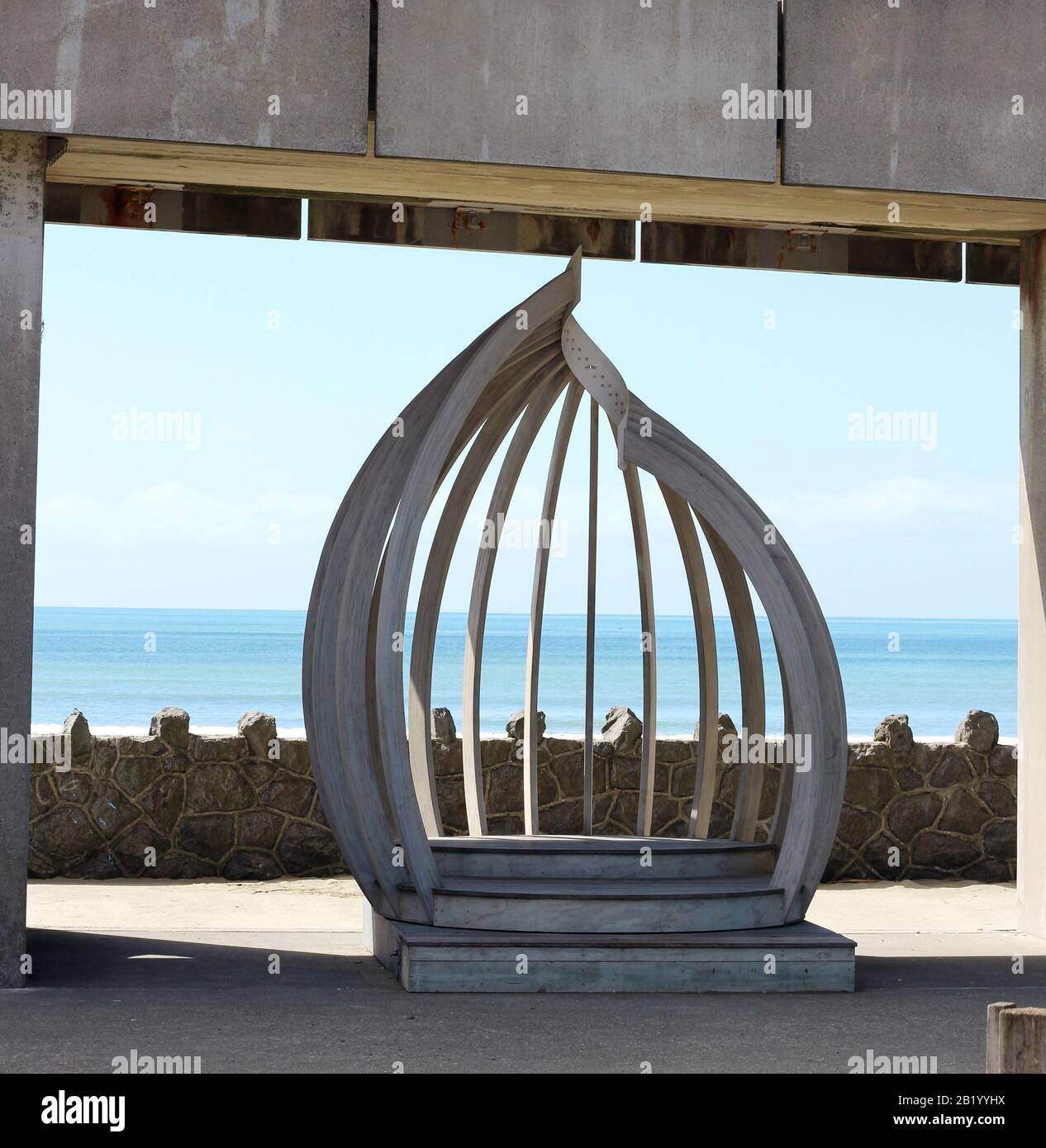 Die organische Form der Skulptur steht im Kontrast zu Betonblöcken, New Brighton Beach, NZ. Die Shell-Kapelle von Ting Lin ist Teil des Kunstprojekts Tiny Huts Stockfoto