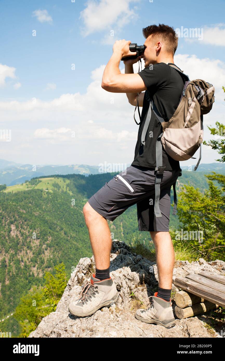 Aktiver Junger Mann, der mit Ferngläsern in eine Berglandschaft blickt Stockfoto