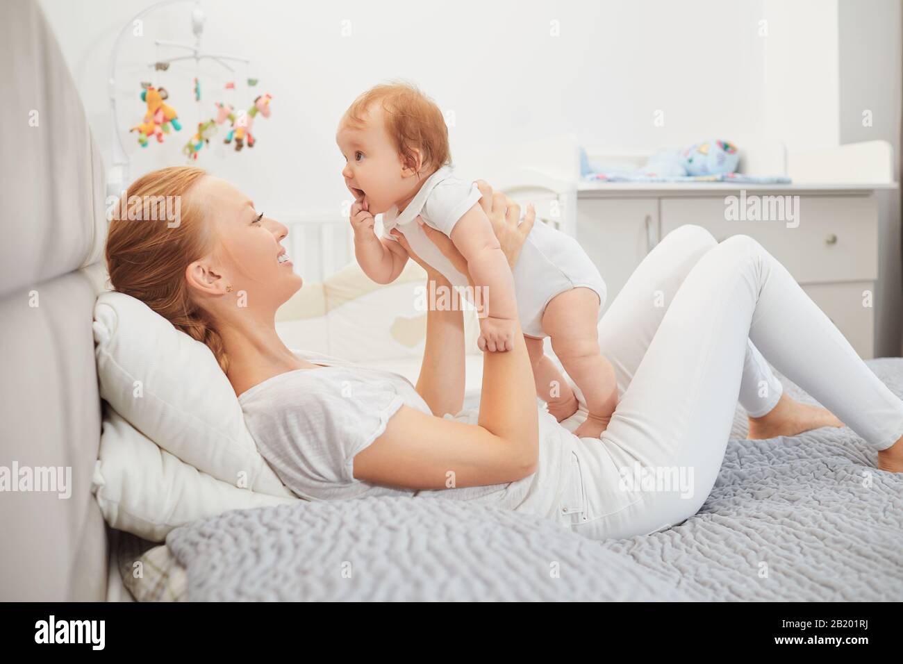 Glückliche Mutter bei Babyspiel im Bett Stockfoto