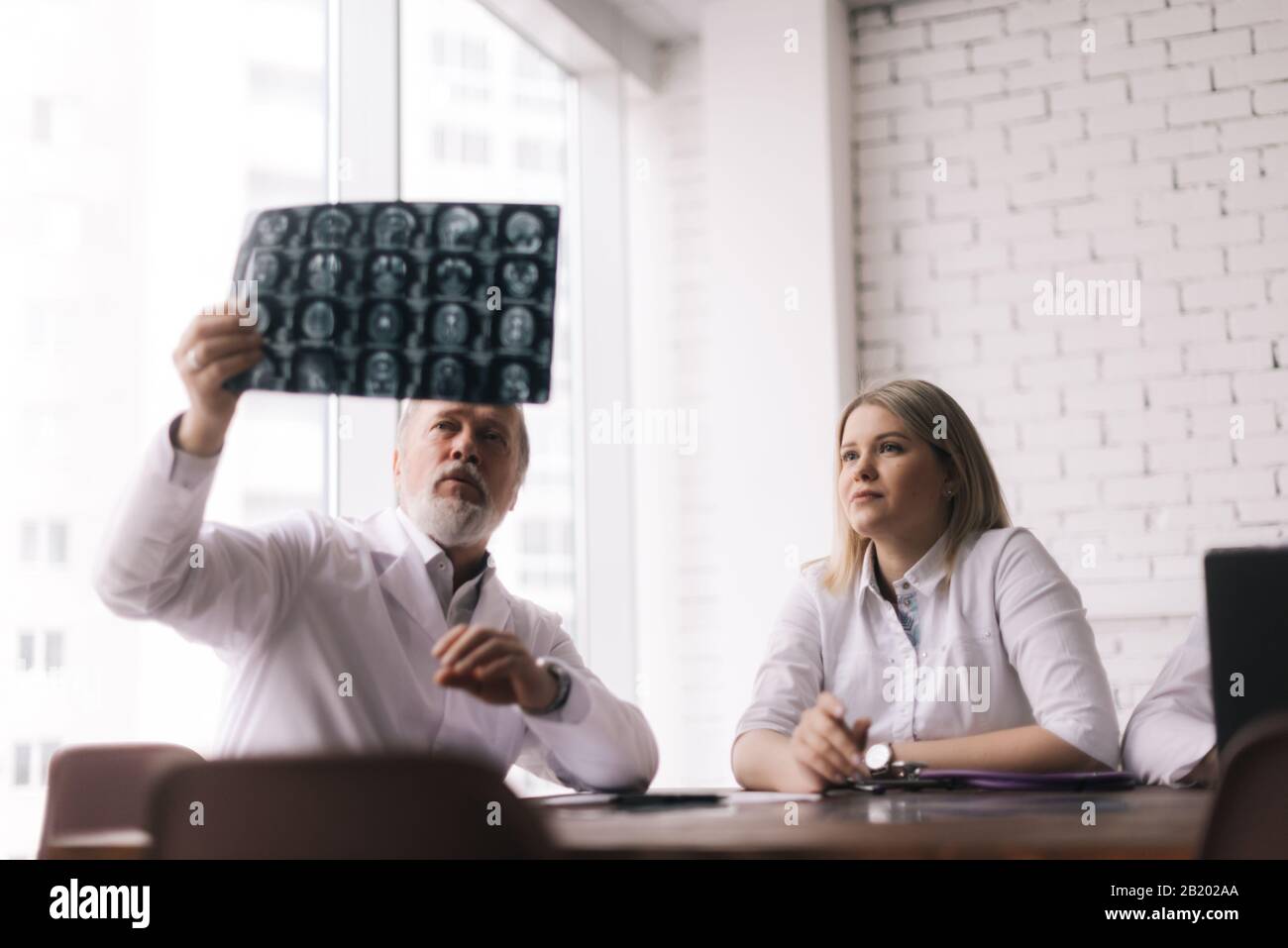 Das Team von drei Ärzten diskutiert die Röntgenaufnahme des Patienten im Beratungszimmer des Krankenhauses Stockfoto