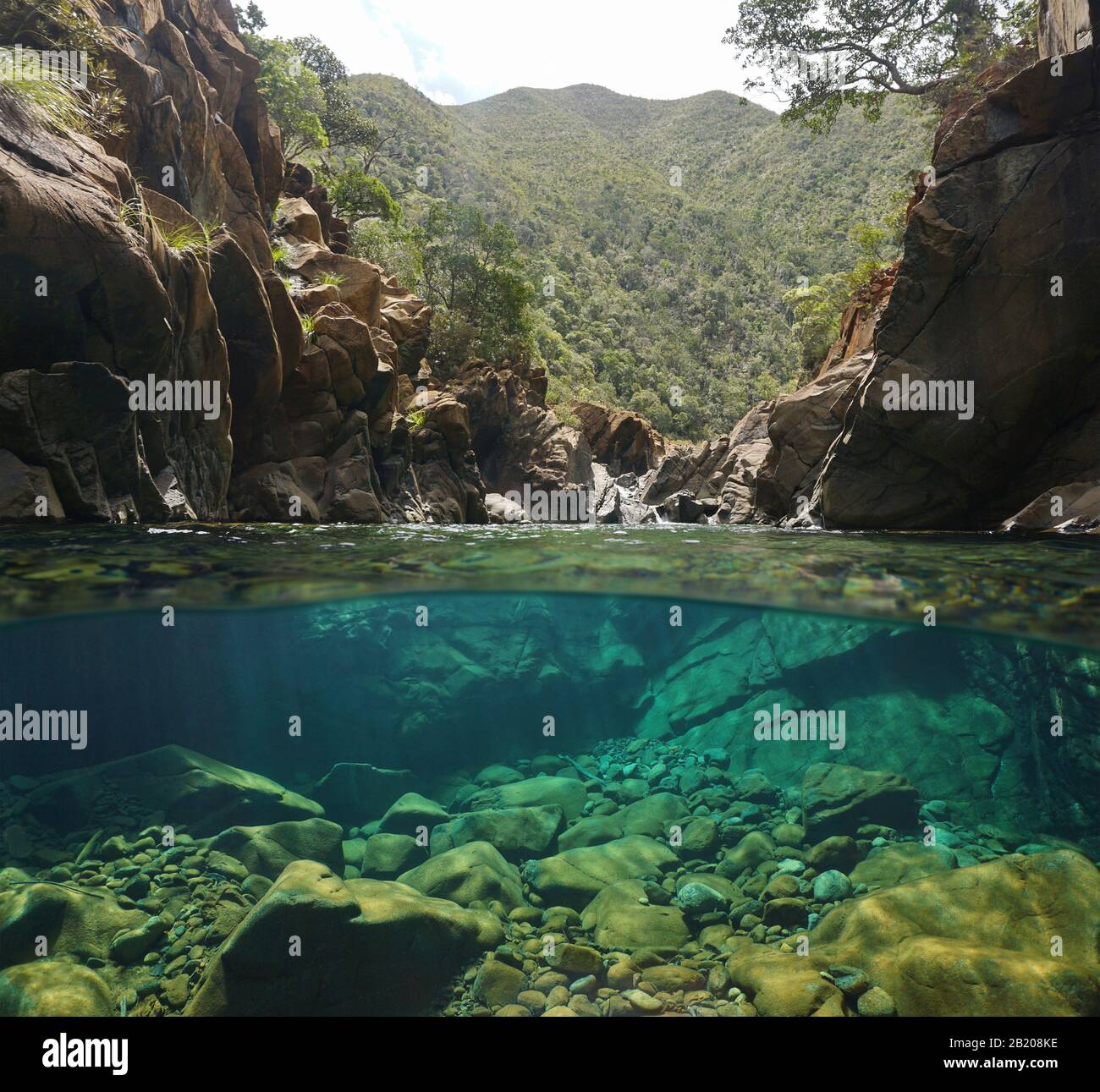 Felsiger Fluss mit klarem Wasser, geteiltem Blick über und unter der Wasseroberfläche, Oceania, Neukaledonien, Dumbea Stockfoto