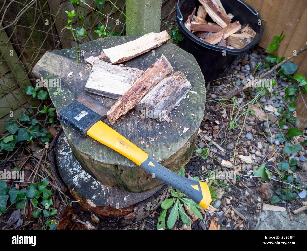 Eine Axt auf einem Hackblock mit gehacktem Anzünden von Holz, das bei einem Hausbrand zum Erhitzen brennt. Stockfoto