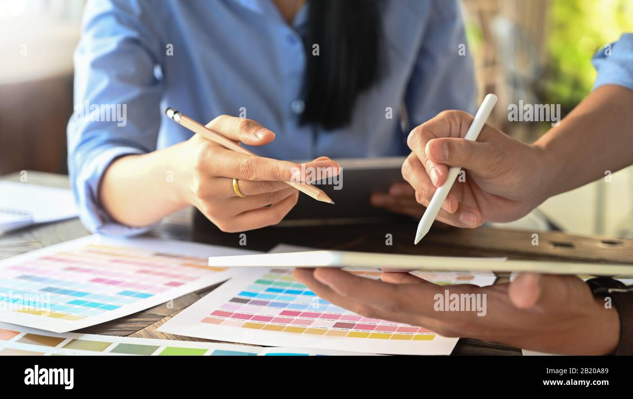 Zugeschnittenes Bild des jungen Grafikdesigner-Teams, das einen Stift und ein Computertablett hält/verwendet, während er über seine neue pr plant/Brainstorming/Diskussionen anhält Stockfoto