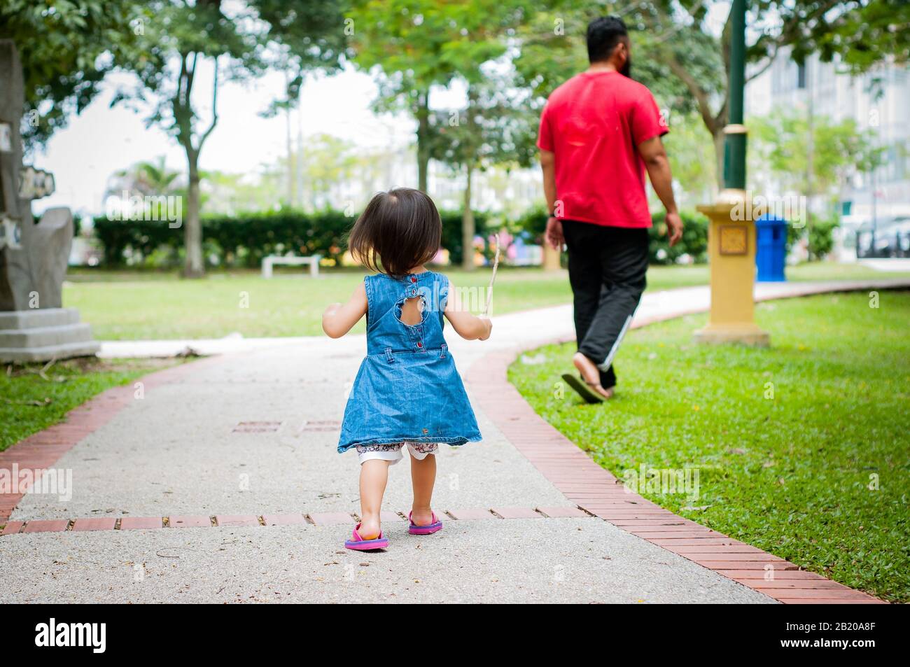 Asiatische 1-jährigen Kleinkind besetzt ist, gehen mit ihrem Vater in einem tropischen Park am Morgen. Exploration und Vaterschaft Konzept. Stockfoto