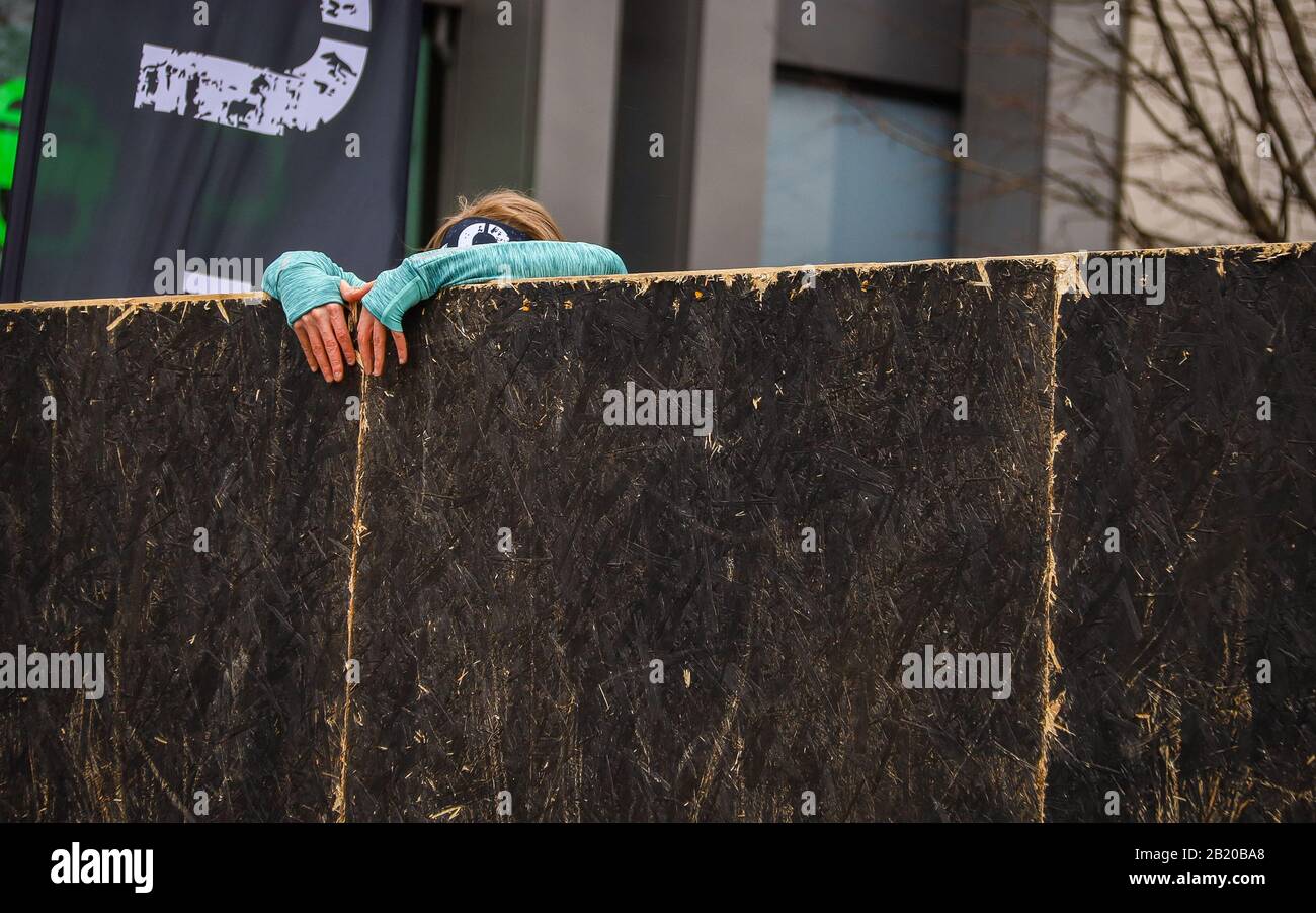 Junge Laufdame, die versucht, während eines spartanischen Rennens über ein Hindernis zu kommen Stockfoto Junge Laufdame, die versucht, während eines spartanischen Rennens über ein Hindernis zu kommen Stockfoto