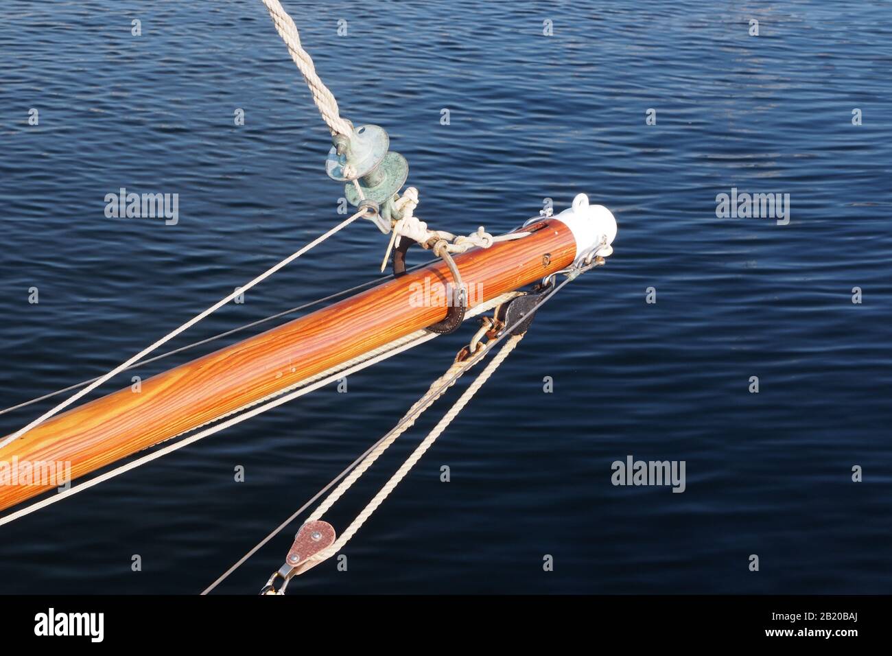 Nahaufnahme eines Bowsprit auf einem Segelboot gegen ein tiefblaues Meer mit einer Klatsche und Takelage Stockfoto