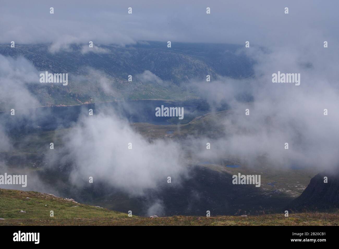 Ein Blick vom Quinag Gebirge hinunter zum Loch Glencoul, Sutherland, Schottland mit wirbelnden weißen, flauschigen Wolken darunter Stockfoto