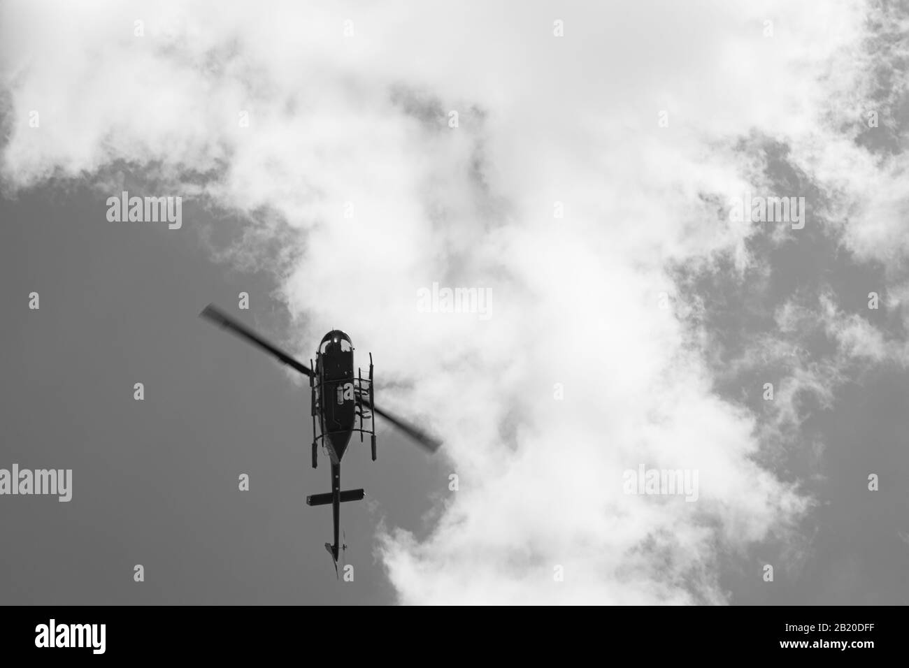 Schwarz-weißes Bild des Hubschraubers, der durch den Himmel fliegt Stockfoto