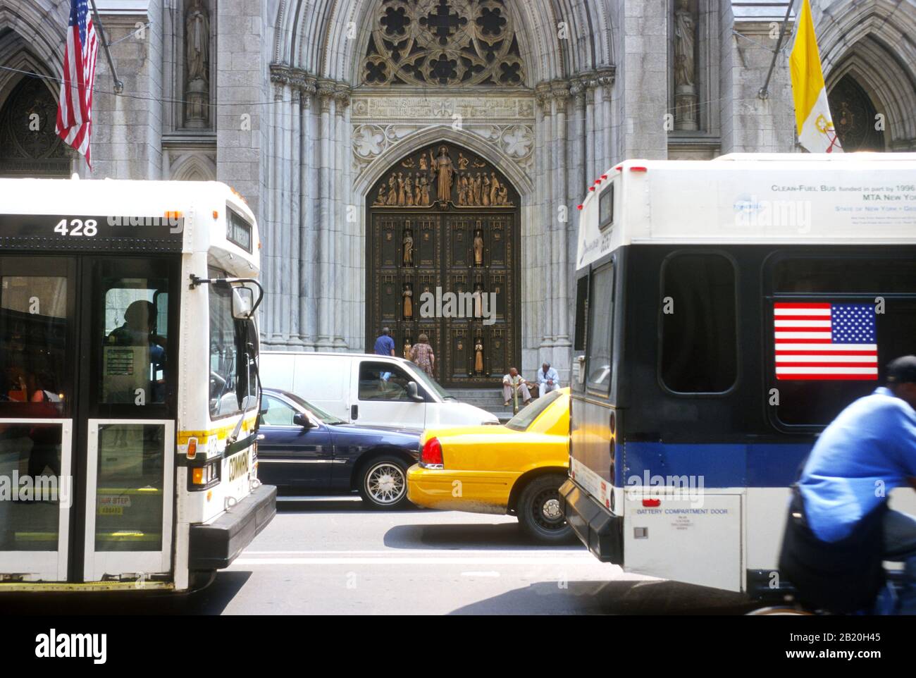 Die Tür zur St. Patrick's Church, New York City mit Autos und New Yorker Bussen, die vorbei fahren Stockfoto