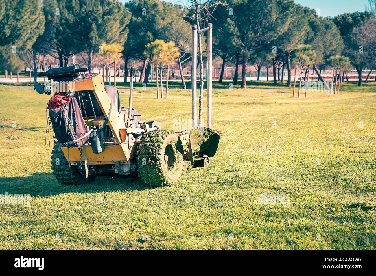 Traktor mäandrierung schmutzigen Grases nach Wartung einer Parkwiese Stockfoto