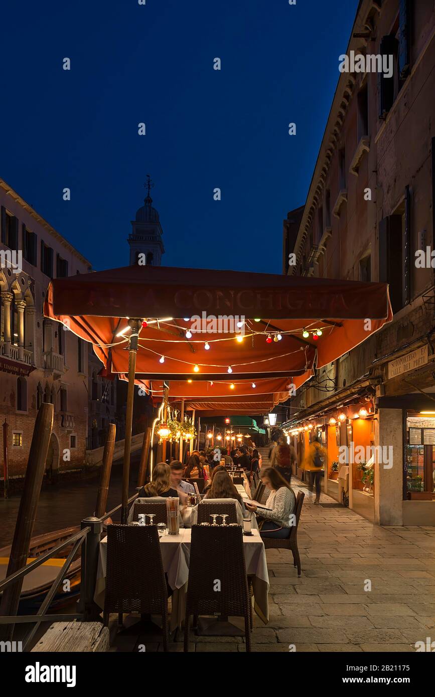 Abends ein lebhaftes Restaurant an einem Kanal hinter dem Turm von Santa Maria della Pieta, Venedig, Venetien, Italien Stockfoto