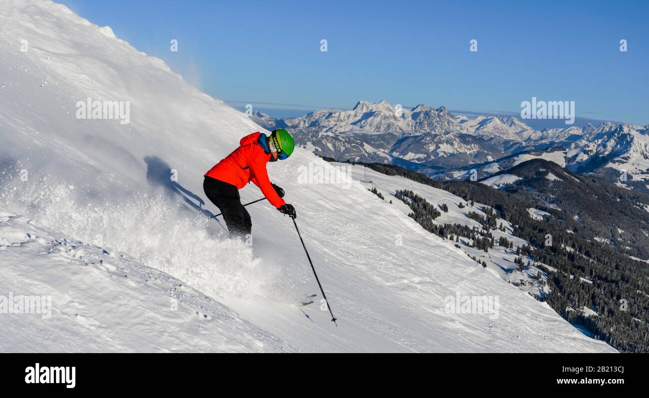 Skifahrer, die auf steilem Hang hinunterfahren, schwarze Piste, blauer Himmel, Berge dahinter, SkiWelt Wilder Kaiser, Brixen im Thale, Tyrol, Österreich Stockfoto