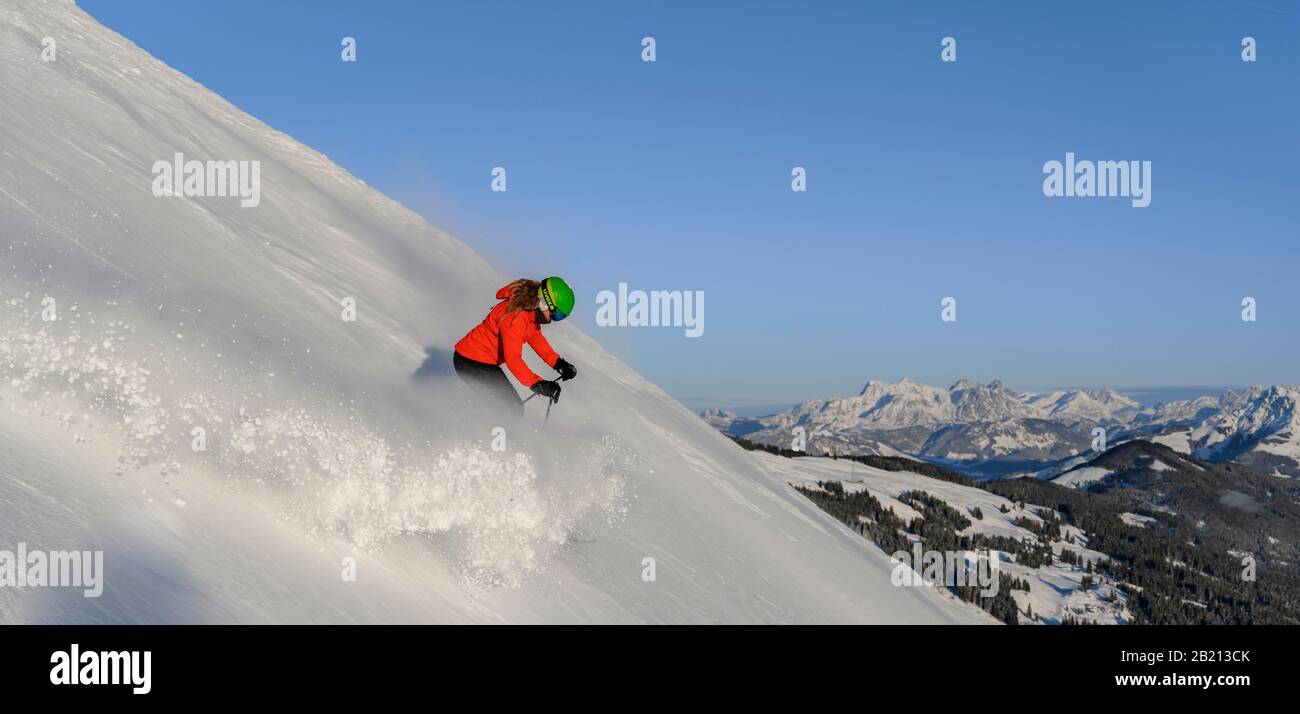 Skifahrer, die auf steilem Hang hinunterfahren, schwarze Piste, blauer Himmel, Berge dahinter, SkiWelt Wilder Kaiser, Brixen im Thale, Tyrol, Österreich Stockfoto