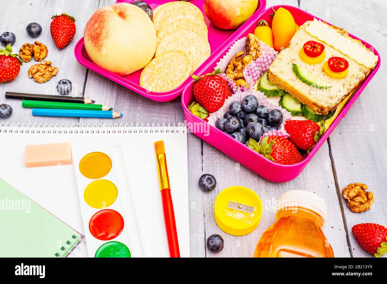 Schul-Mittagsbox mit Sandwich, frischem Obst, Gemüse, Plätzchen, Saft und Nüssen. Gesunde Essgewohnheiten für Kinder. Zurück zum Schulkonzept. Mit der Schule Stockfoto