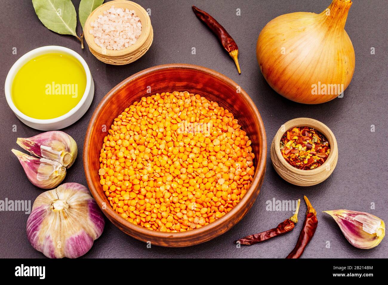 Rohe Zutaten für Dish tarka dal, Daal Curry, traditionelle indische Dhal würzige Curry-Suppe. Rotes trockenes Linsen, Knoblauch, Chili, Zwiebel, Öl. Schwarzer STON Stockfoto