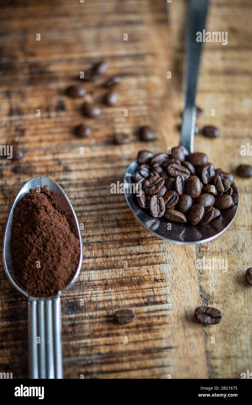 Löffel auf einem Tisch mit Kaffeebohnen und Kaffeepulver Stockfoto