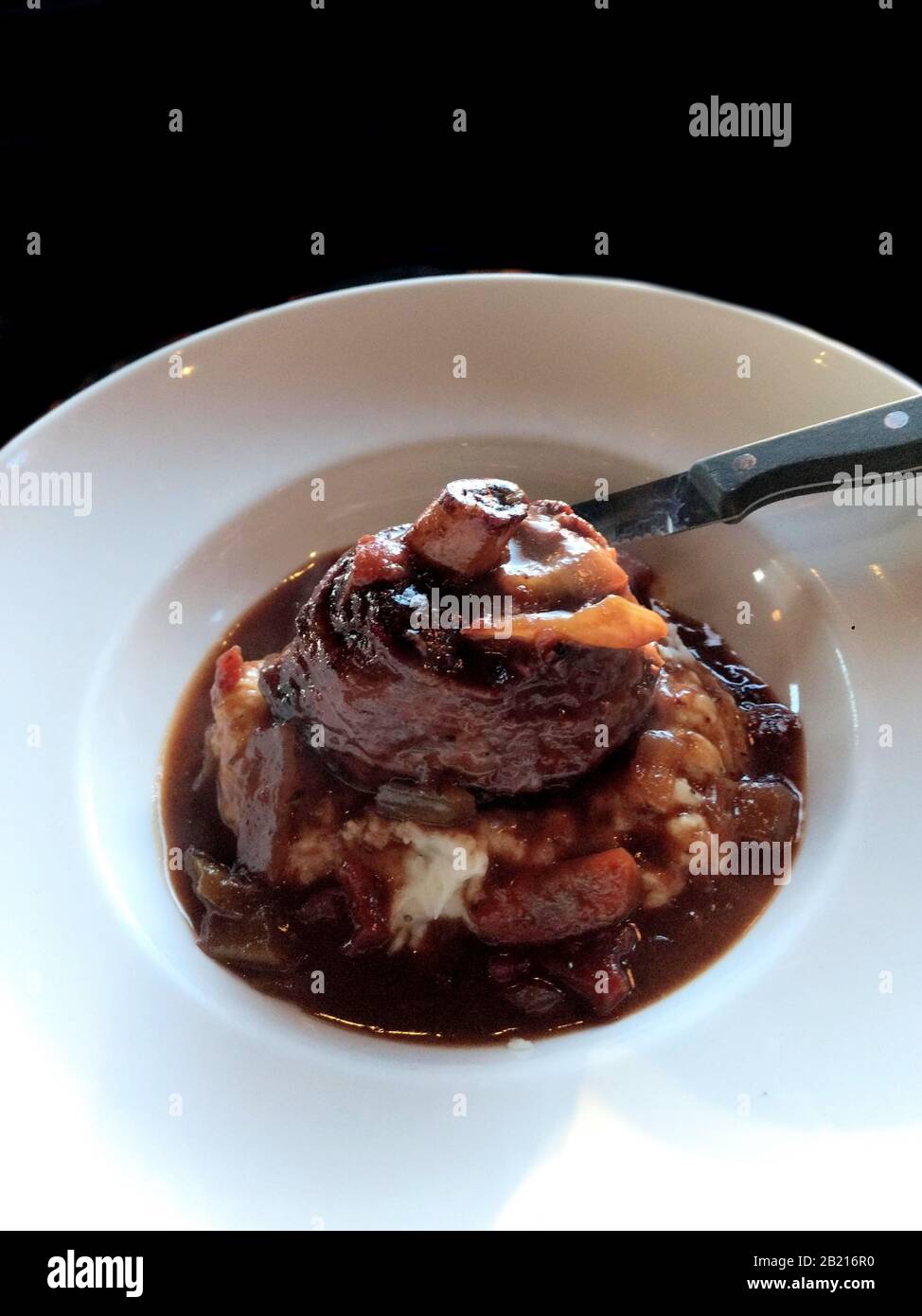 Geschmortes Lamb Osso Bucco auf einem Bett aus cremigem Knoblauchpüree, Kartoffelpüree und in einem Gemüse-Ratatouille erstickt. Stockfoto