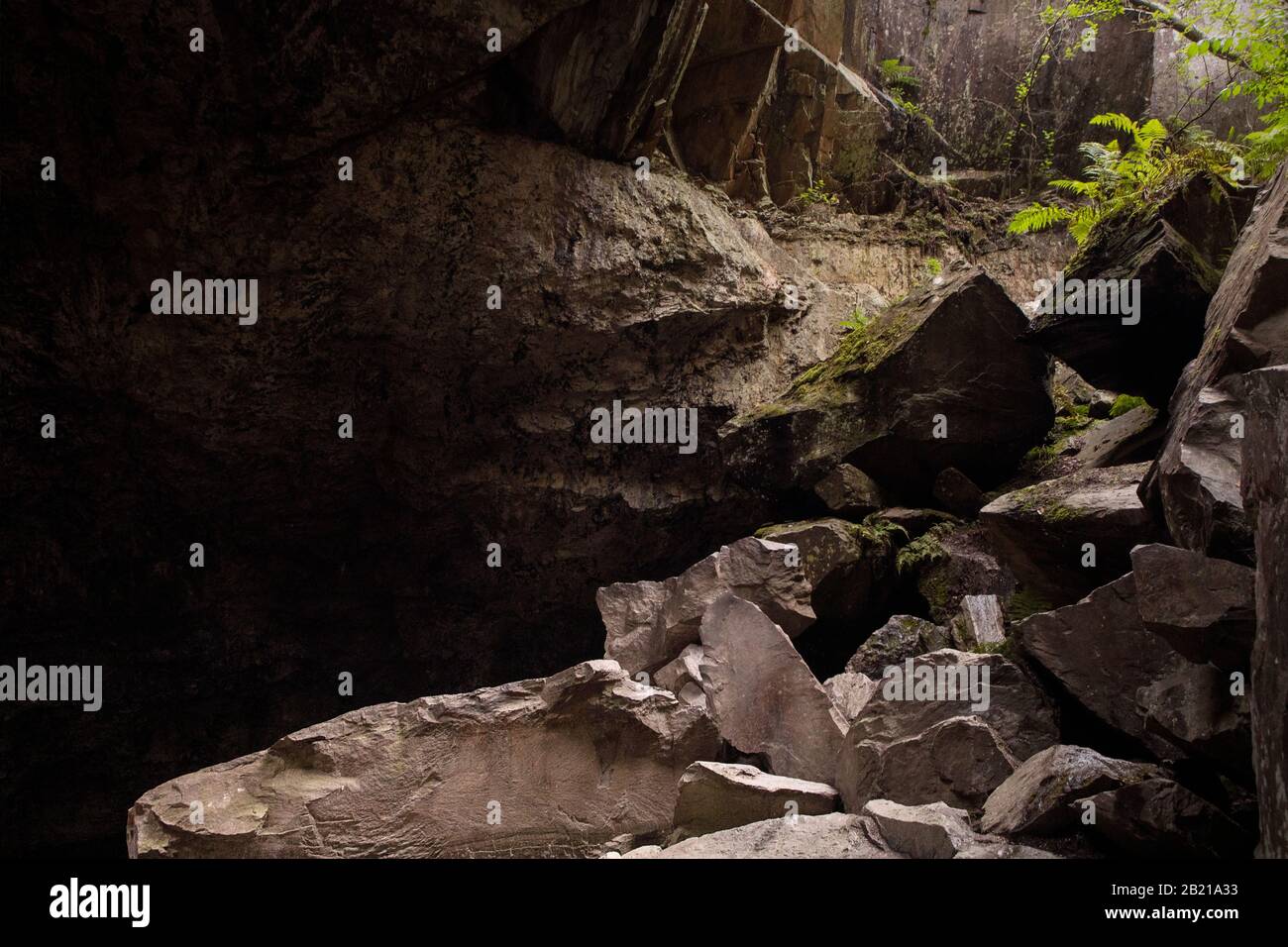 Felshaufen am Ende des dunklen Höhlenkorridors. Auslass der Höhle mit sichtbarem Licht. Nesodden, Norwegen. Stockfoto