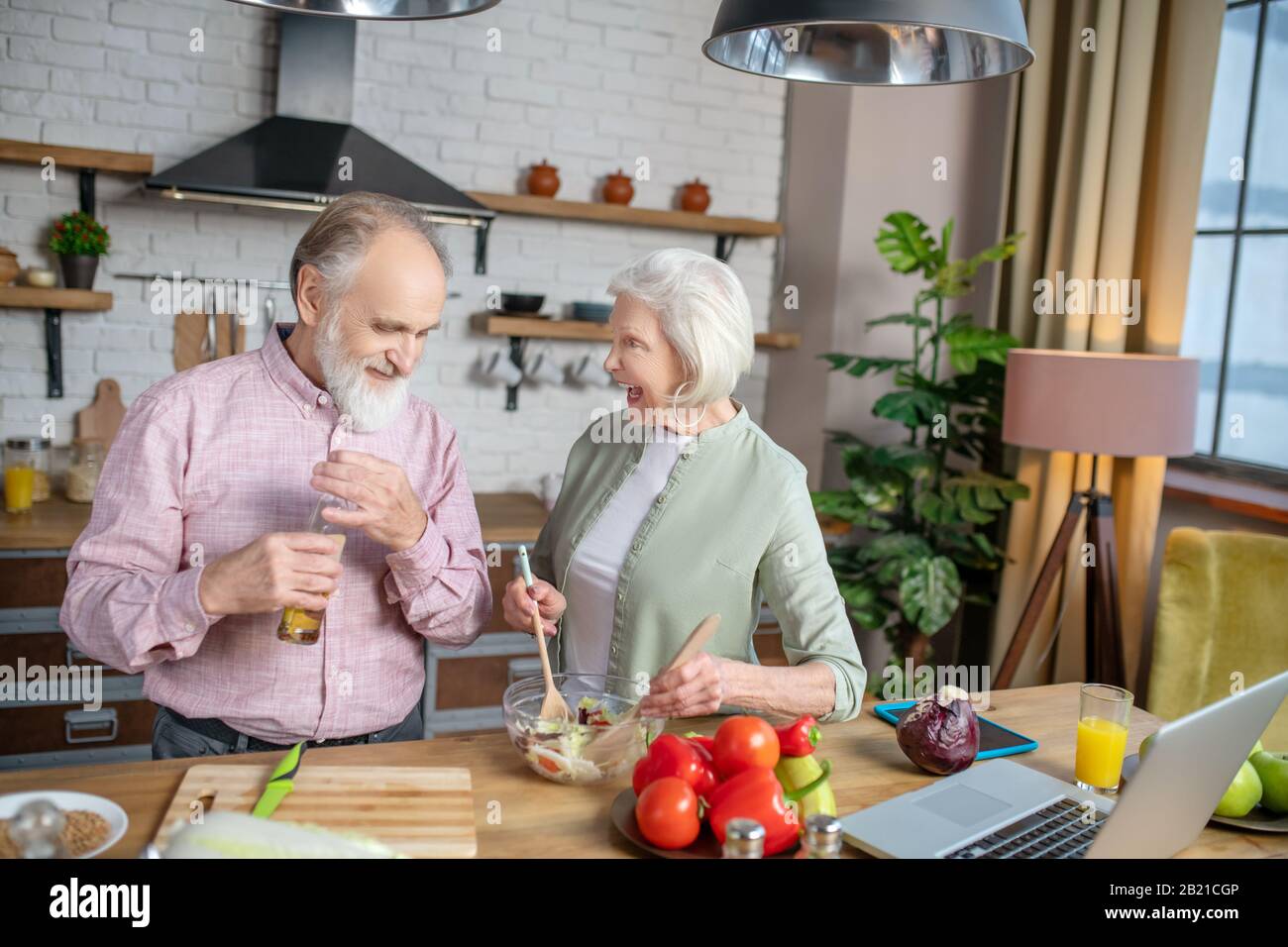 Ältere Menschen unterhalten sich beim gemeinsamen Kochen lebhaft Stockfoto