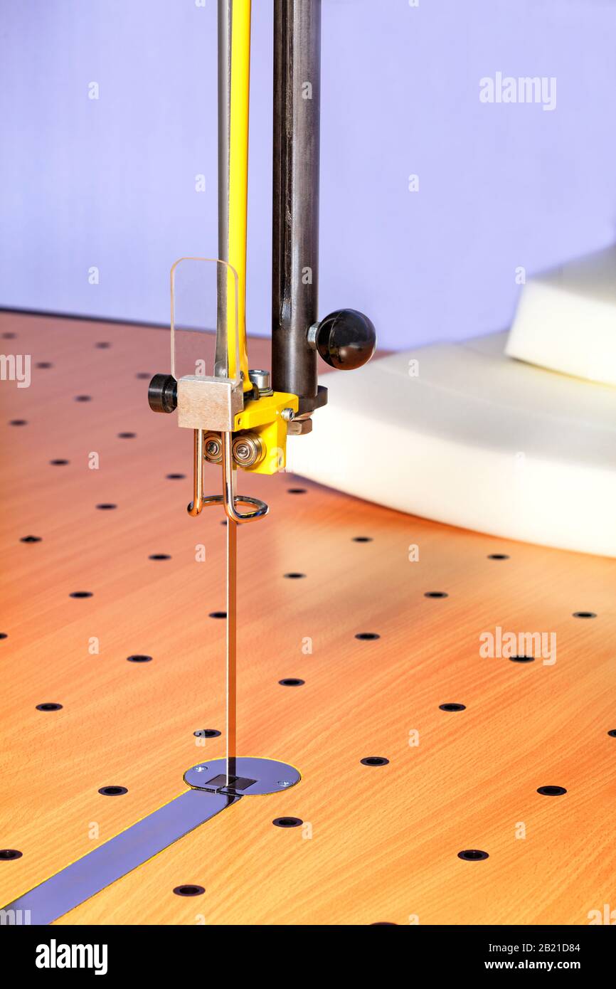 Eine dünne Säge auf einem modernen Schneidtisch und einer Maschine zum Schneiden von Schaumgummi sorgt für hochpräzises Schneiden, Nahaufnahme. Stockfoto