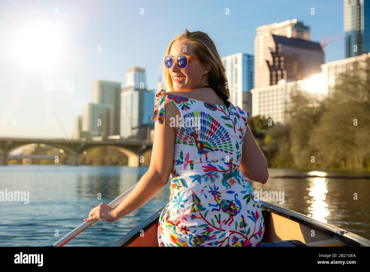 Fröhliche, fröhliche junge Frau in der Sonnenbrille, die einen heißen Sommertag mit Wasseraktivitäten, Bootstouren, Kajak und Kanufahren in Austin Texas genießt Stockfoto