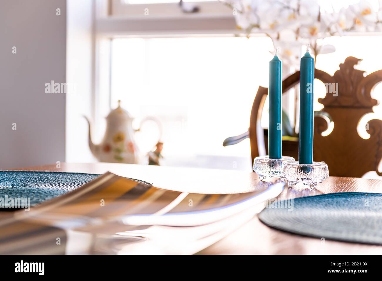 Zwei blaue Kerzenstöcke auf dem Tisch im Speisesaal des Hauses mit hellem Fenster im Hintergrund in elegantem Ambiente Stockfoto