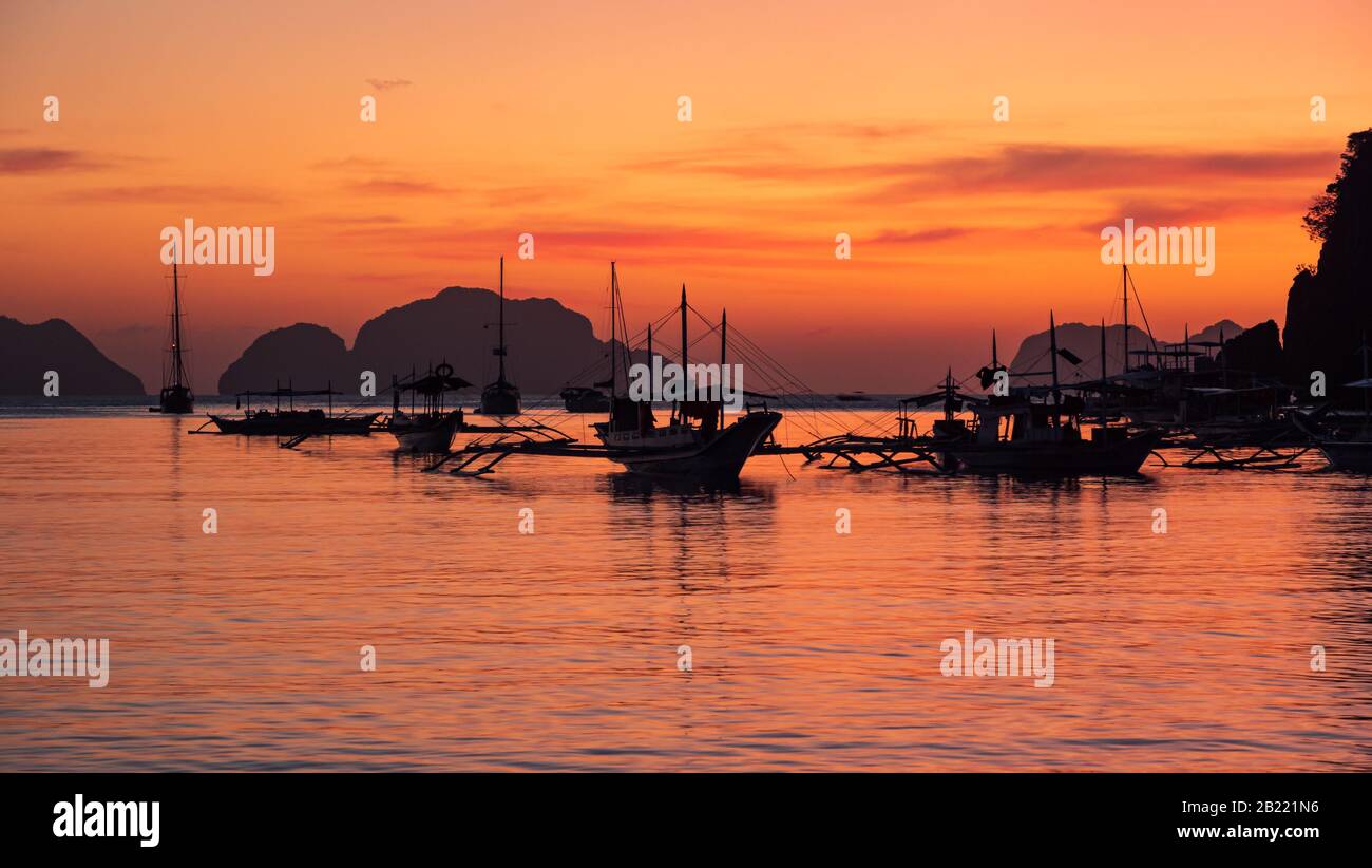 Traditionelles philippinisches Boot bangka bei Sonnenuntergang. Wunderschöner Sonnenuntergang mit Silhouetten philippinischer Boote in El Nido, Palawan Island, Philippinen. Stockfoto