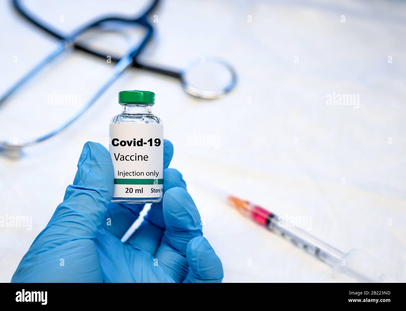 Arzt zeigt Covid-19-Coronavirus Impfstoff mit Stethoskop und Injektionsspritze im Hintergrund; suggestive Abbildung Stockfoto