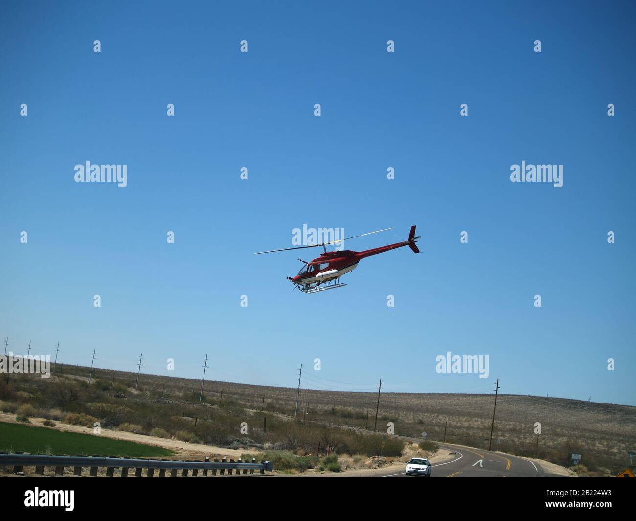Ein Hubschrauber, der einen Tiefpass über eine Straße im Süden Arizonas macht, um ein Erntefeld zu stauben. Stockfoto