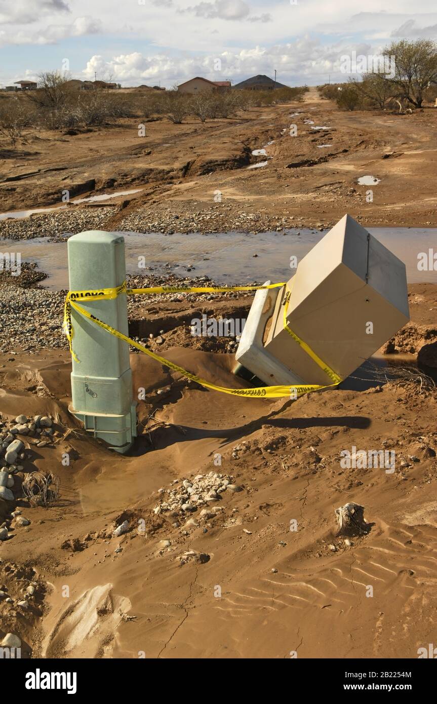 Eine Kreuzung aus Arizona, die von einem Monsoon Regen überschwemmt wurde und den Boden unter einem Stromkasten und einem Telefonanschluss erodierte. Stockfoto