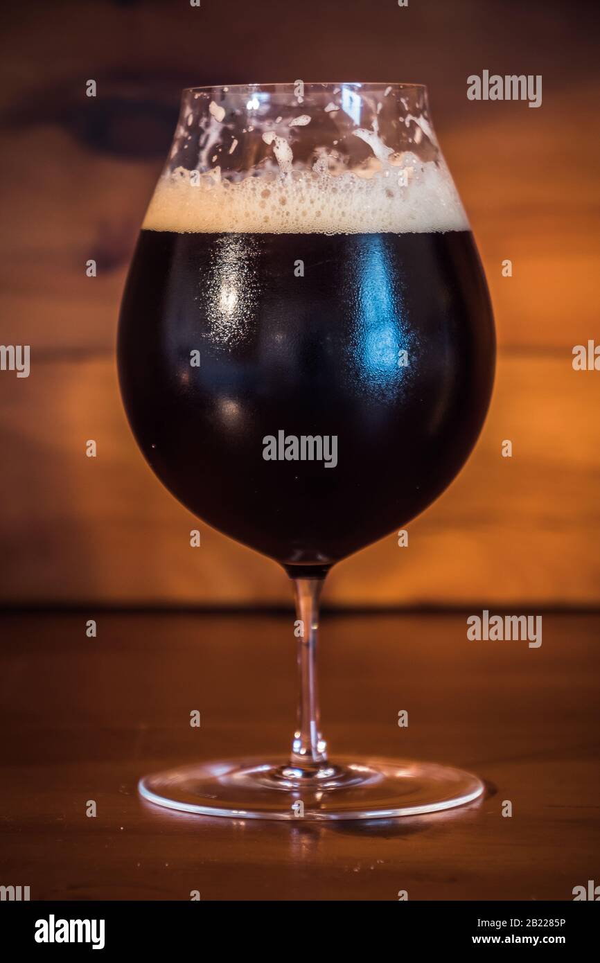 Dunkles Bier oder Ale wie Bamberger Smokebeer in einem Tulpenglas auf Holzhintergrund Stockfoto