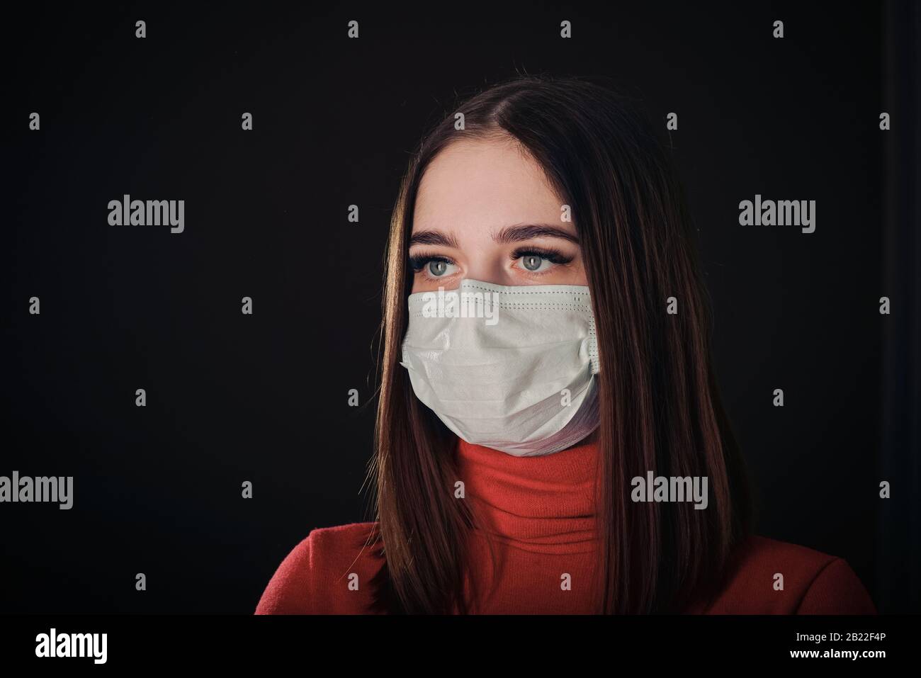 Grippe kalt oder Allergie Symptom. Kranke junge Frau, die in Maske niest, isoliert auf schwarzem Hintergrund. Gesundheitswesen. Studio gedreht. Geschäftsfrau trägt eine Maske und Stockfoto