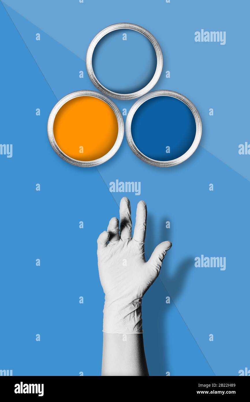 Ein dreifarbiges blaues Hintergrundbild mit drei farbigen Farbdosen und einer schwarz-weißen Frauenhand in einem Handschuh. Stockfoto
