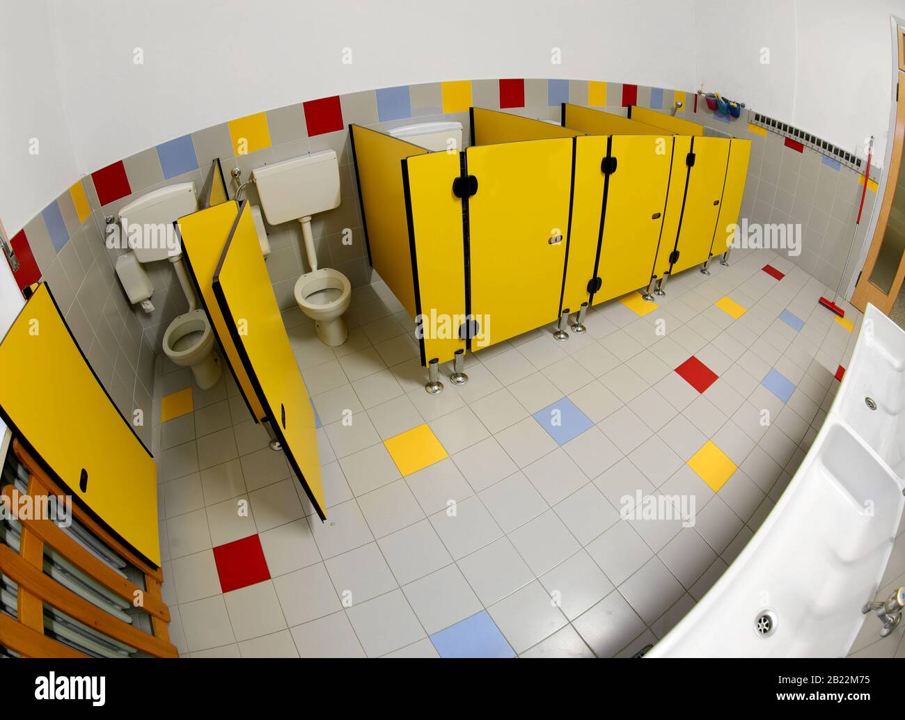 Viele gelbe Türen eines breiten Badezimmertabors eines Kindergartens ohne Menschen mit Fischaugenobjektiv Stockfoto