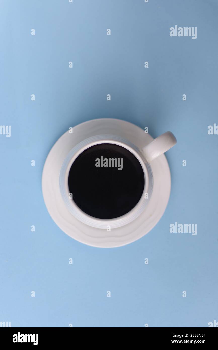 Draufsicht über Kaffee in Tasse mit Schaum auf blauem Hintergrund, schwarzer Kaffee mit Schaum auf dem Oberteil Stockfoto