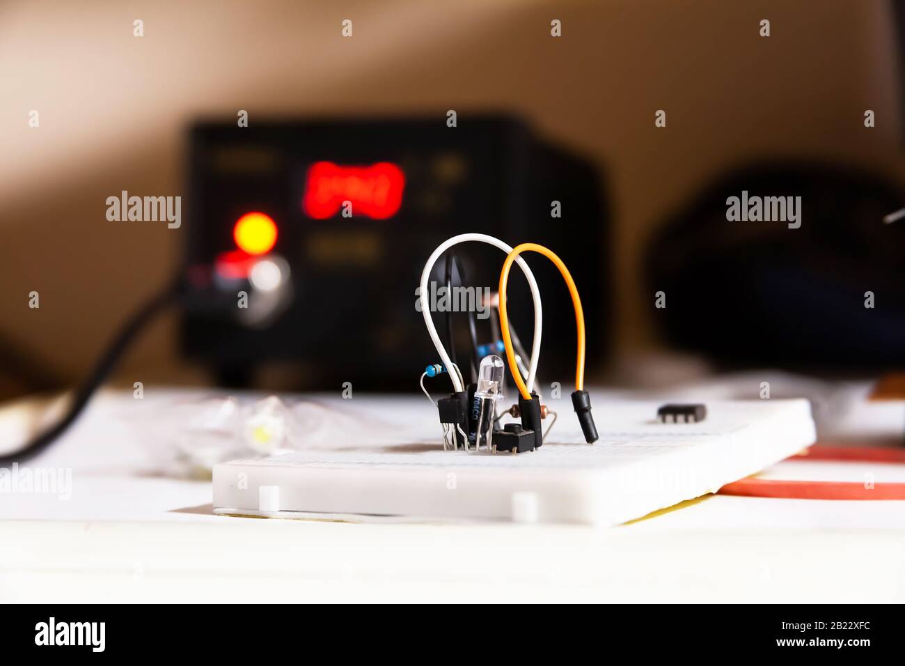 Einfacher Stromkreis, weiße Steckkarte mit elektrischen Komponenten, Drähten, Dioden, Widerständen, Lötstation im Hintergrund, Projekt Stockfoto