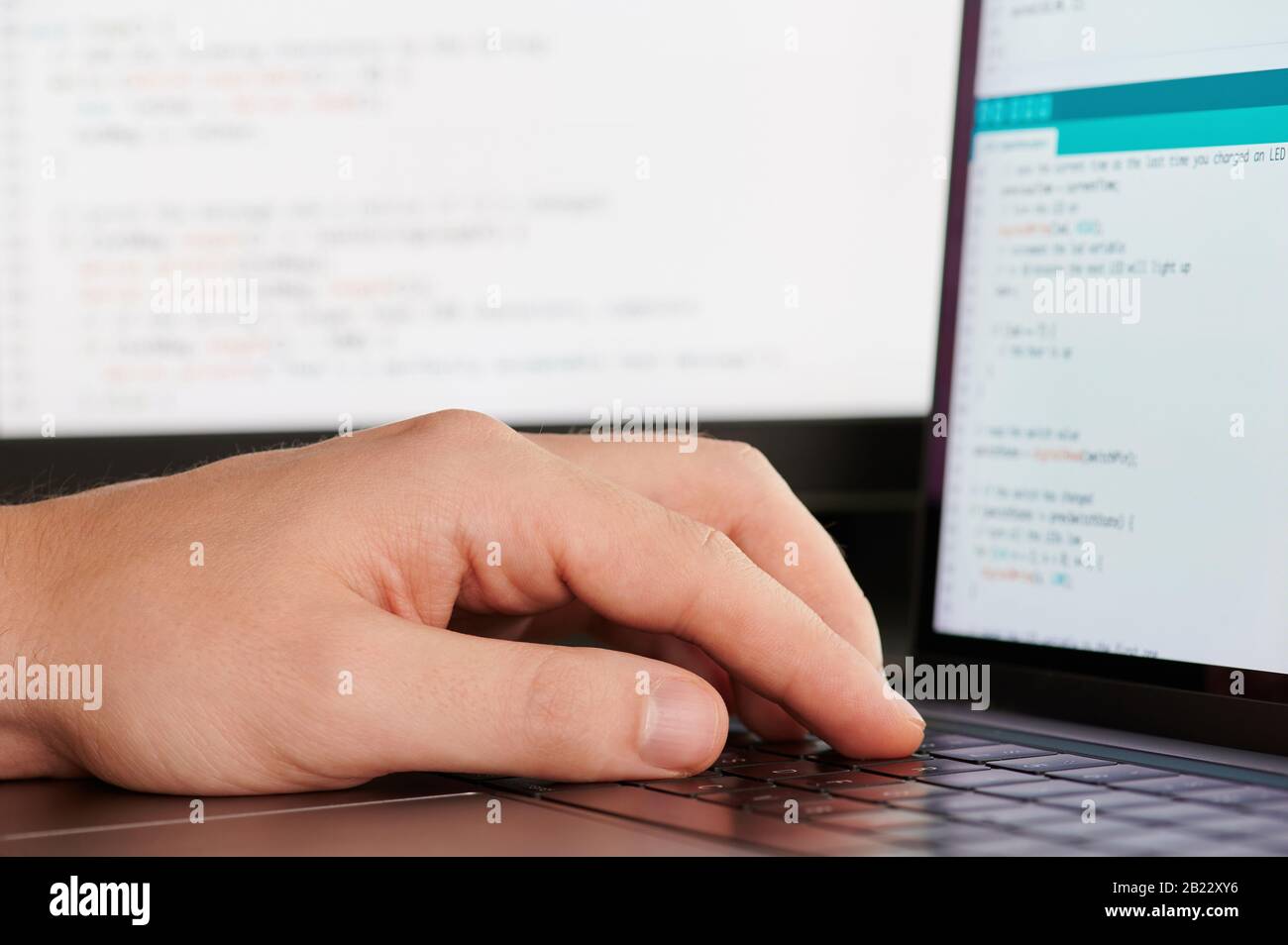 Eine Hand auf der Tastatur im Programm-Skript verschwommener Hintergrund Stockfoto