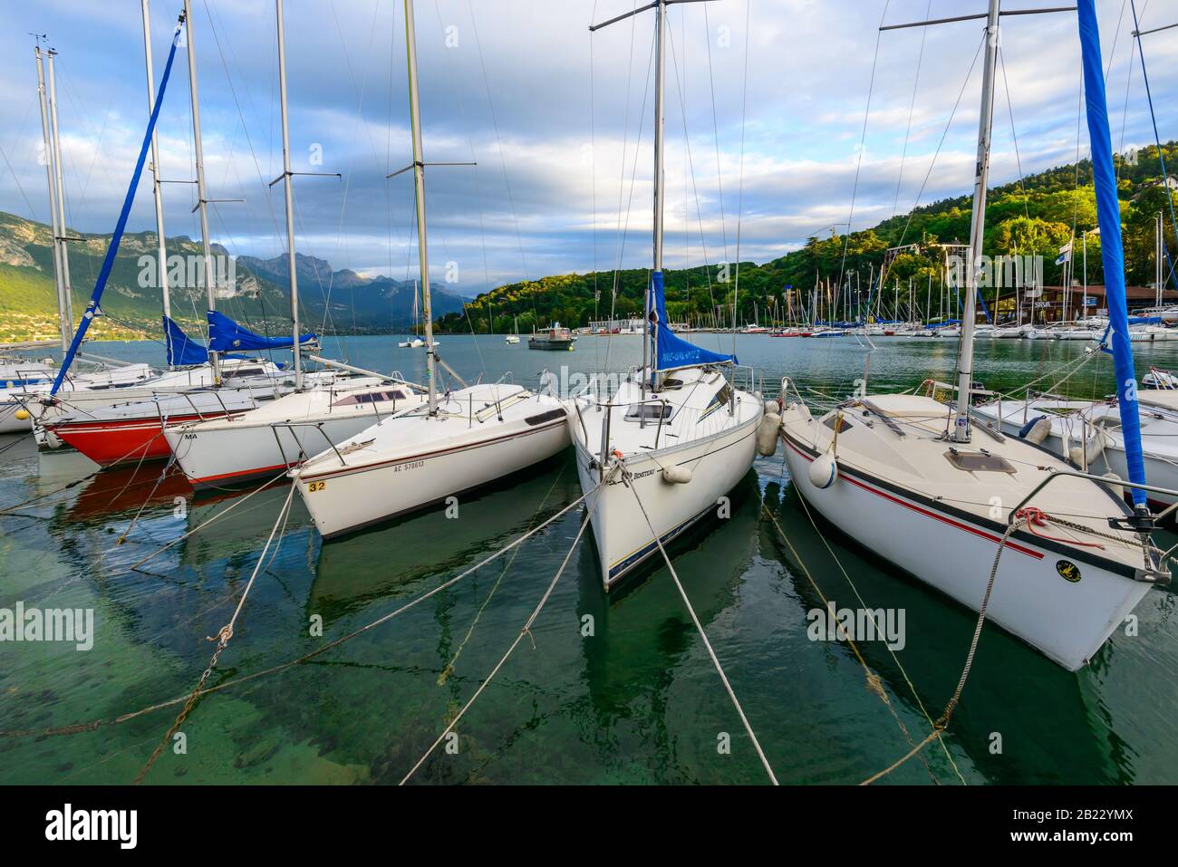 Segelboote, die auf dem See von Annecy, einem der größten Seen in Frankreich, der als sauberster See Europas bekannt ist, bei Sonnenuntergang festgemacht wurden. Stockfoto