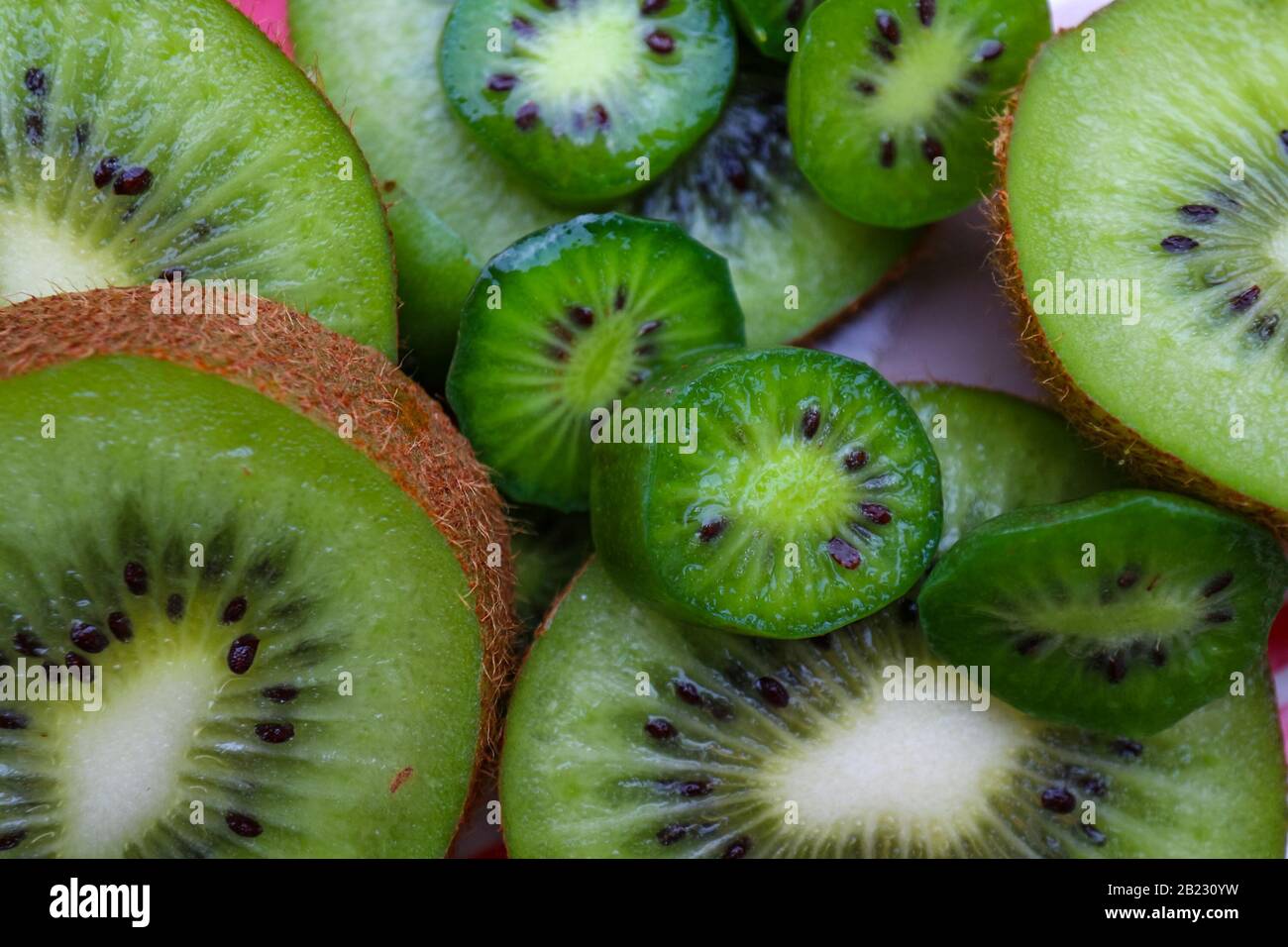 Nahaufnahme von geschnittenem Kiwi-Obst und Kiwi-Beeren. Stockfoto