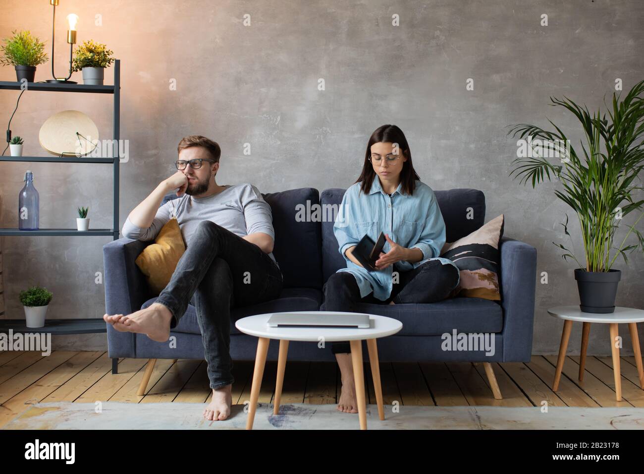 Junges Paar Sitzt auf dem Sofa. Die Frau Reißt Das Foto Auf. Familienkonflikt. Stockfoto