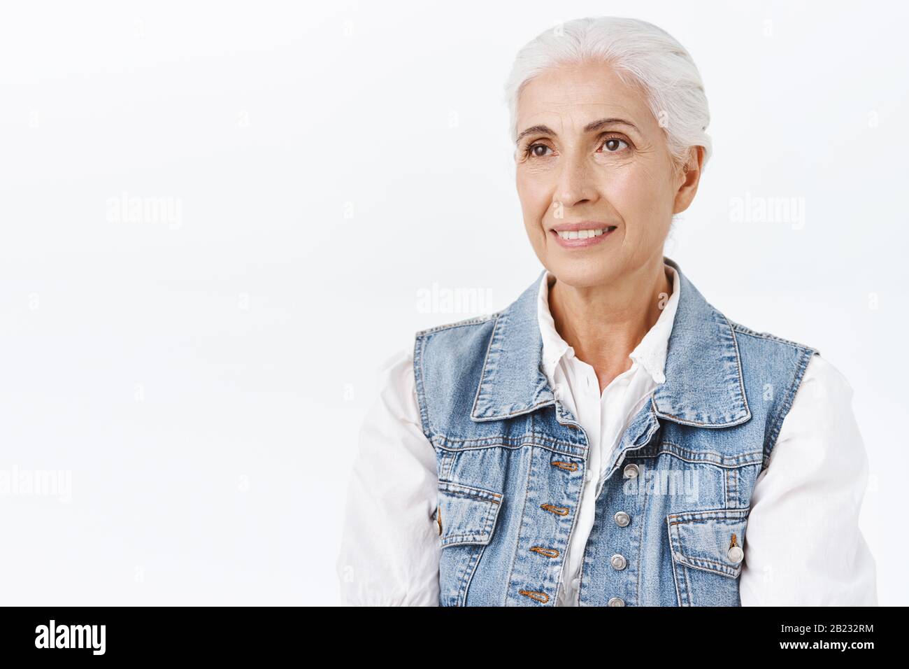 Verträumte, unbeschwerte, lächelnde alte Frau träumt davon, Enkelkinder während der weihnachtsfeier der Familie zu treffen, sie grinst beiseite und denkt darüber nach Stockfoto