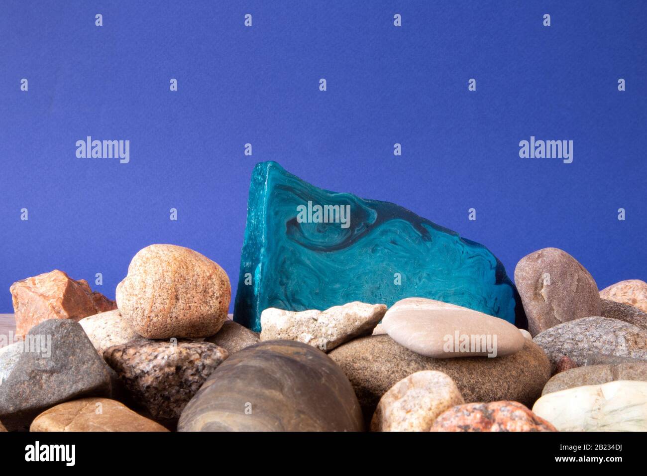 Dünnes flaches Stück blaue Minze handgemachte Seife auf einem Kieselhaufen vor violettem Hintergrund Stockfoto